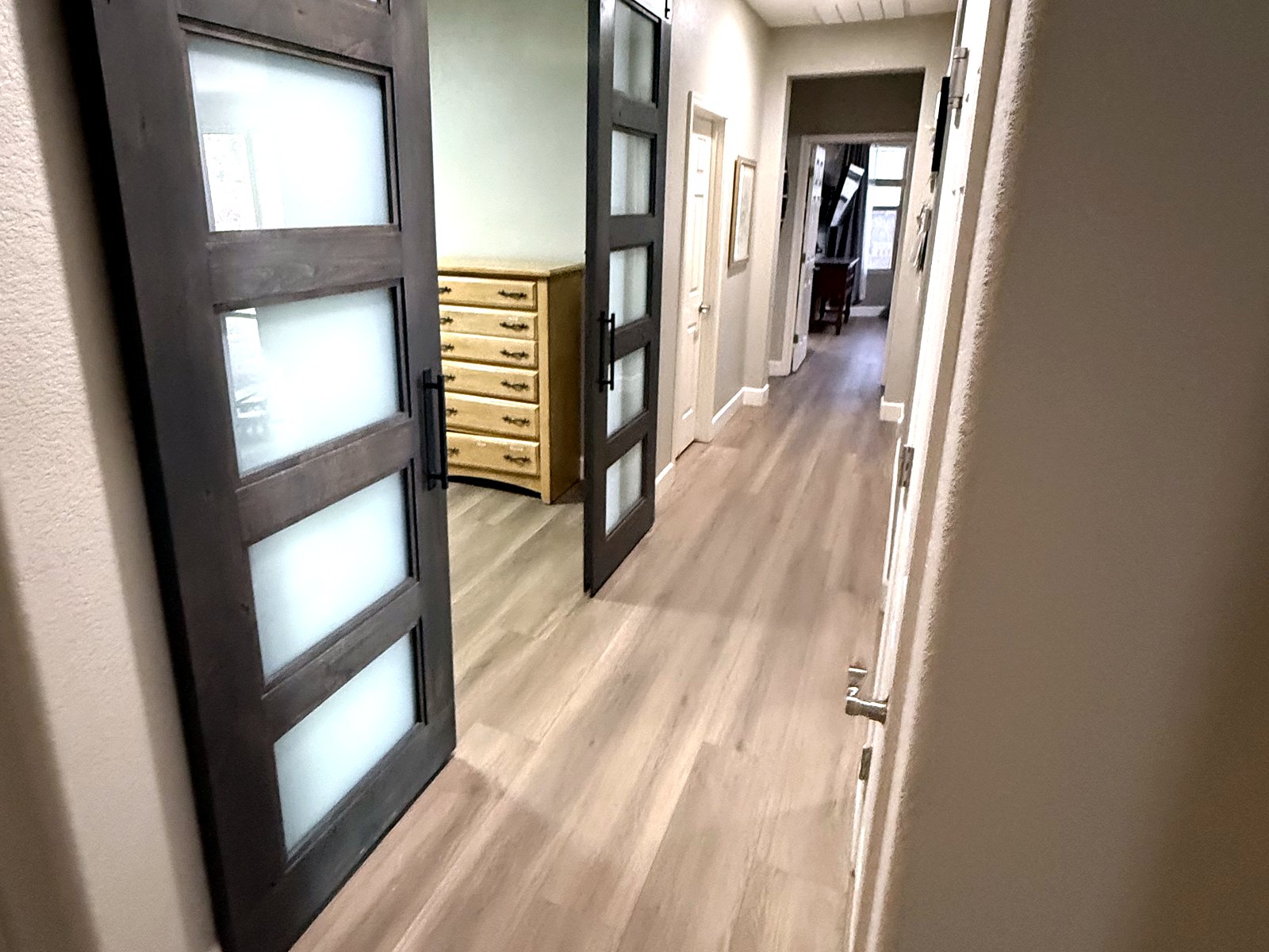 Wood-look vinyl plank flooring running through a hallway with barn doors